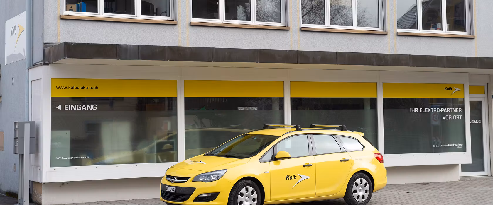 Gelbes Servicefahrzeug der Kolb Elektro SBW AG vor dem Firmengebäude
